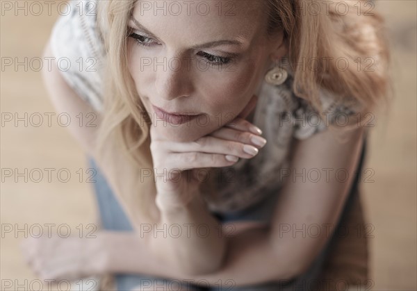 Mid-adult woman sitting on chair, thinking.