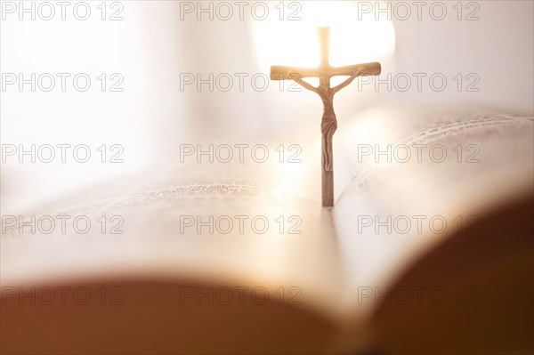 Backlit cross in open Bible.