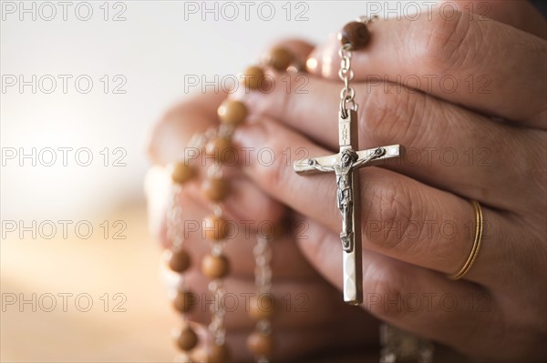 Woman praying with rosary beads in hands.