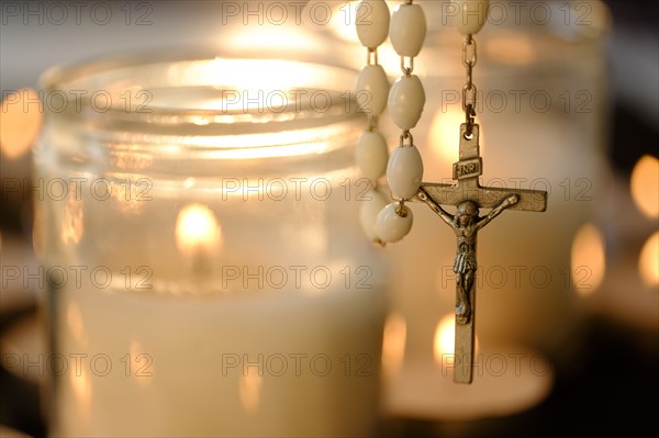 Burning candles with rosary in foreground.