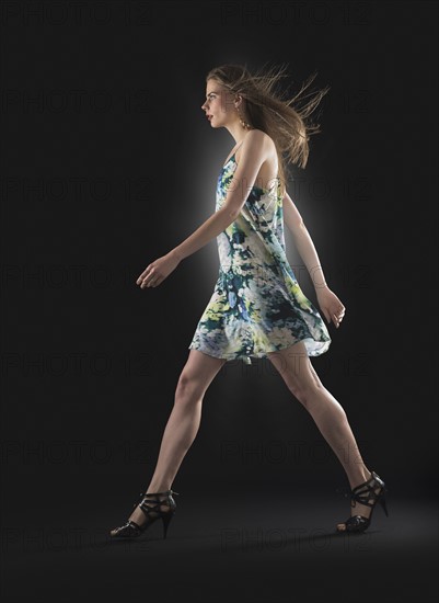 Studio shot of young woman walking.