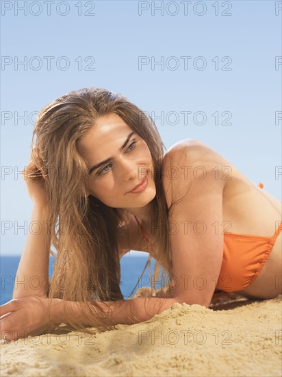 Portrait of young woman lying on beach.