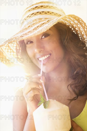 Young woman having drink in sunlight.