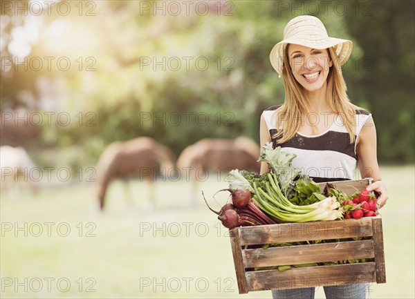 Woman carrying fresh vegetables in box.