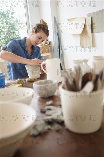 Young woman making pottery in studio.