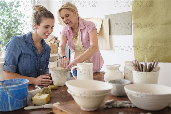 Two women making pottery in studio.