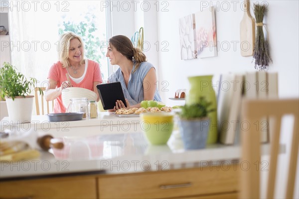 Mother with adult daughter baking in kitchen.