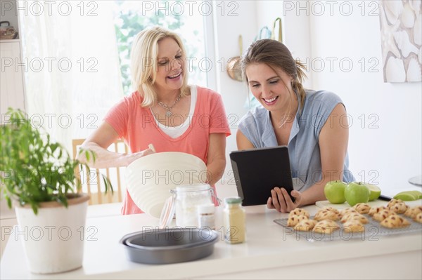 Mother with adult daughter baking in kitchen.