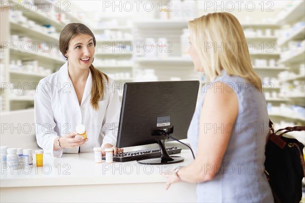 Patient talking to pharmacist in pharmacy.