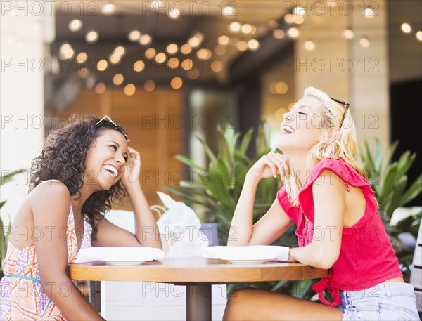 Female friends laughing in street cafe