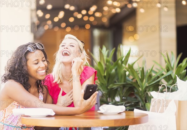 Female friends using smart phone in cafe
