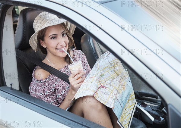 Smiling woman with map in car.