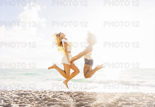 Female friends jumping on beach