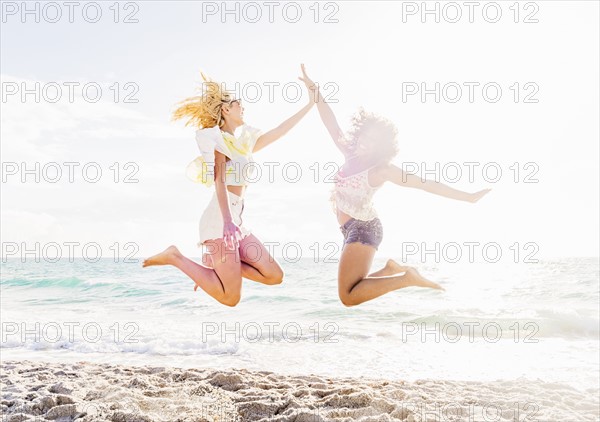 Female friends jumping on beach