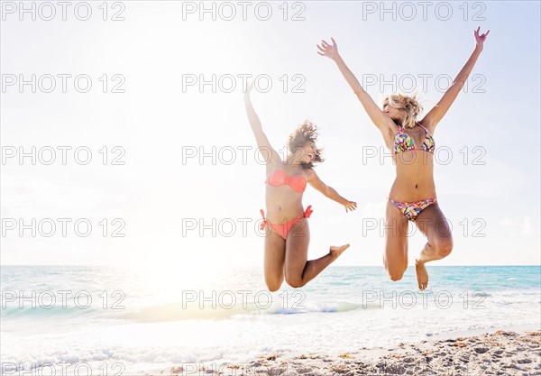 Female friends jumping on beach