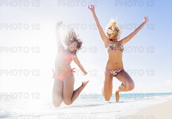 Female friends jumping on beach