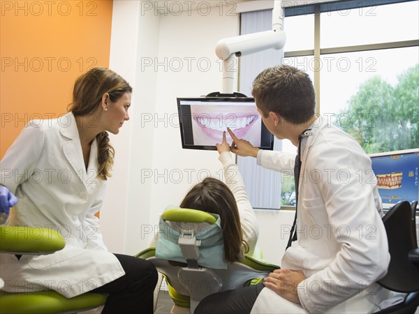 Dentists and patient looking at screen