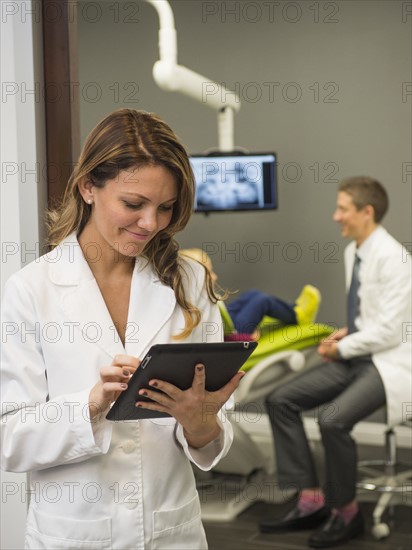 Portrait of dentist with colleague and patient (8-9) in background