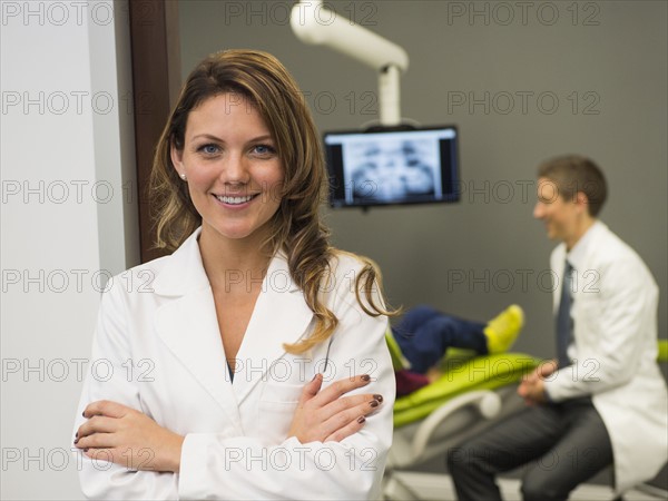 Portrait of dentist with colleague and patient (8-9) in background