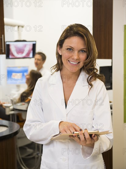 Portrait of dentist with colleague and patient in background