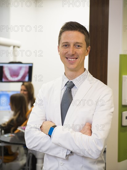 Portrait of dentist with colleague and patient in background