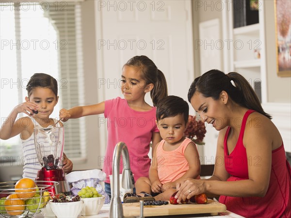 Mother and children (2-3, 6-7, 8-9) preparing fruit cocktails