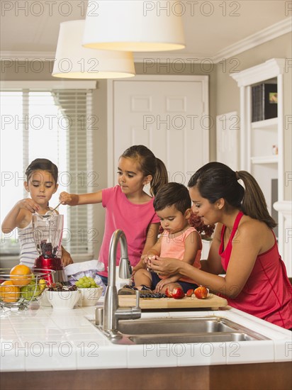 Mother and children (2-3, 6-7, 8-9) preparing fruit cocktails