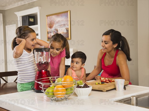 Mother and children (2-3, 6-7, 8-9) preparing fruit cocktails