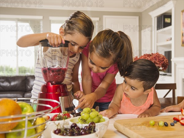 Children (2-3, 6-7, 8-9) preparing fruit cocktails