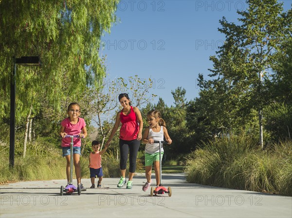 Pregnant mother and children (2-3, 6-7, 8-9) walking outdoors