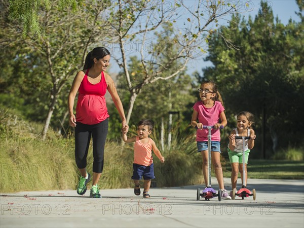 Pregnant mother and children (2-3, 6-7, 8-9) walking outdoors
