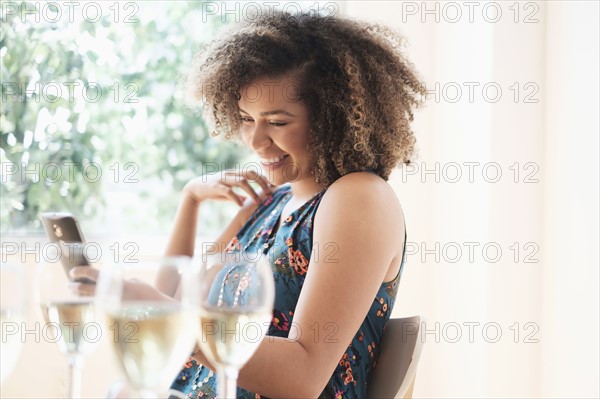 Young woman using smart phone at restaurant.