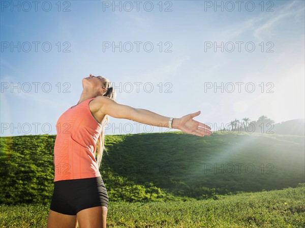 Woman with outstretched arms in field