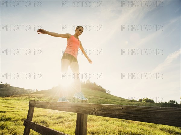 Woman balancing on wooden fence