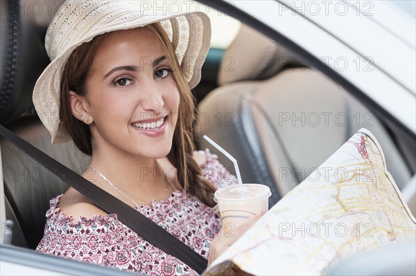 Smiling woman with map in car.