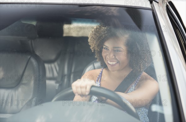 Young woman smiling while driving car.