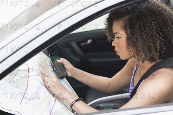 Young woman checking map in car.