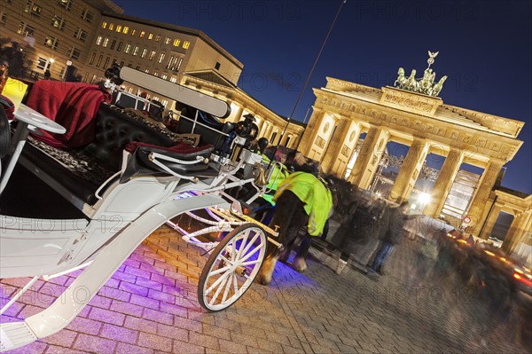 Horse carts in front of illuminated Brandenburg Gate