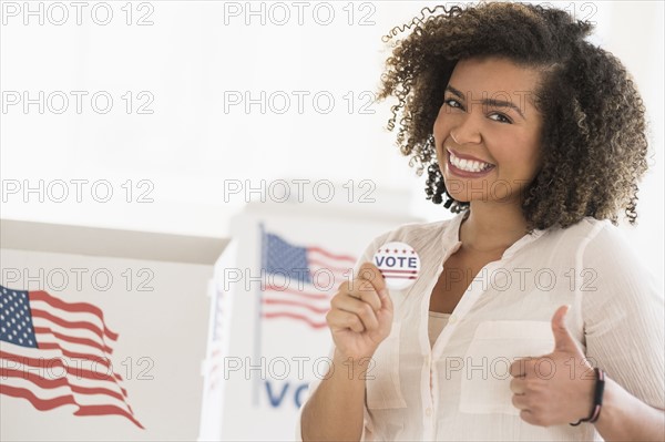 Young woman holding voting badge and smiling.