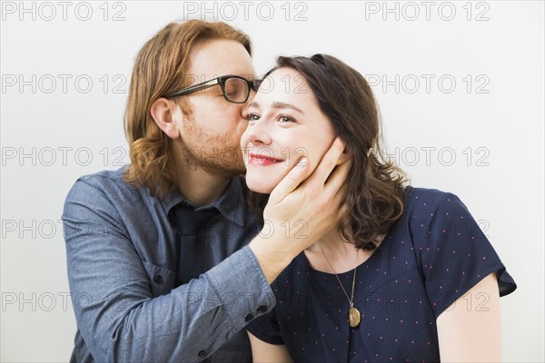 Man kissing smiling young woman