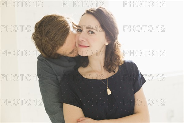 Man kissing smiling young woman