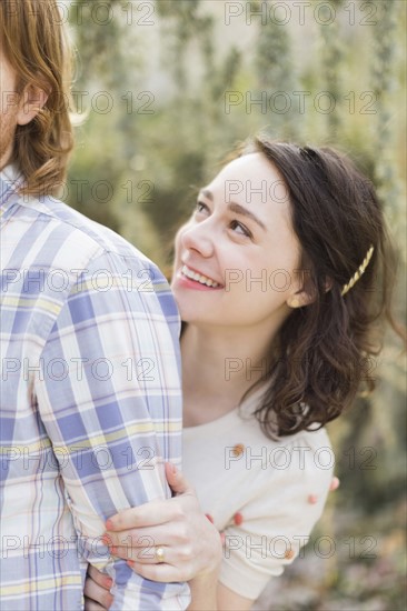 Young woman hiding behind boyfriend