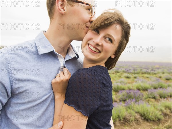 Young couple embracing with field on background