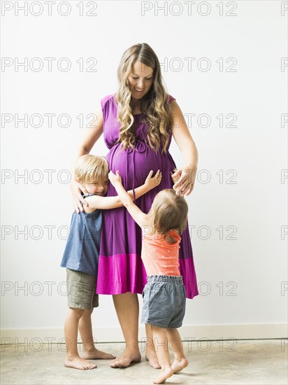 Children (2-3) hugging pregnant mother