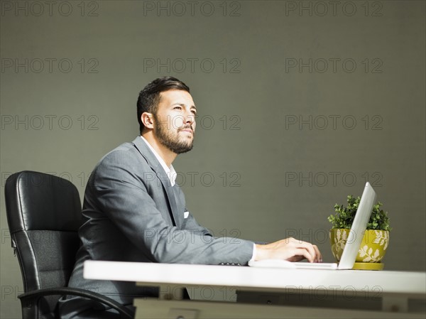 Young man sitting at desk and using laptop