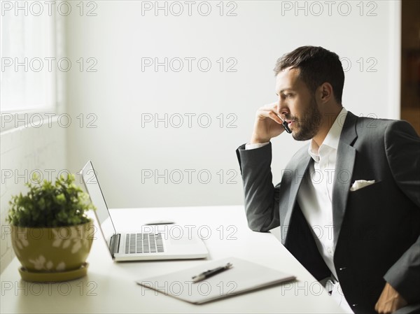Young man sitting at desk and looking at laptop