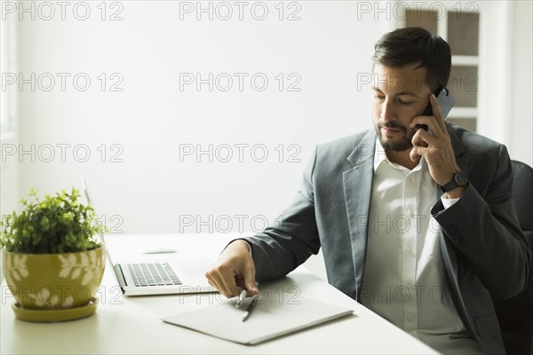 Young man sitting at desk and looking at laptop