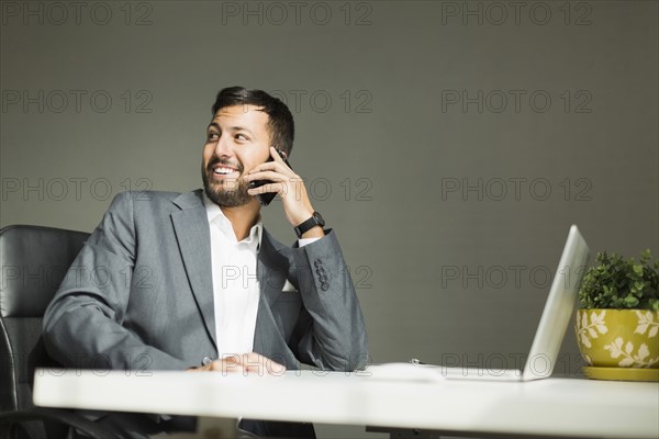Young man sitting at desk and talking on phone