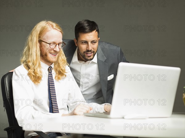 Businessmen looking at laptop in office