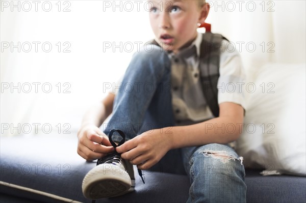 Boy (6-7) tying shoes